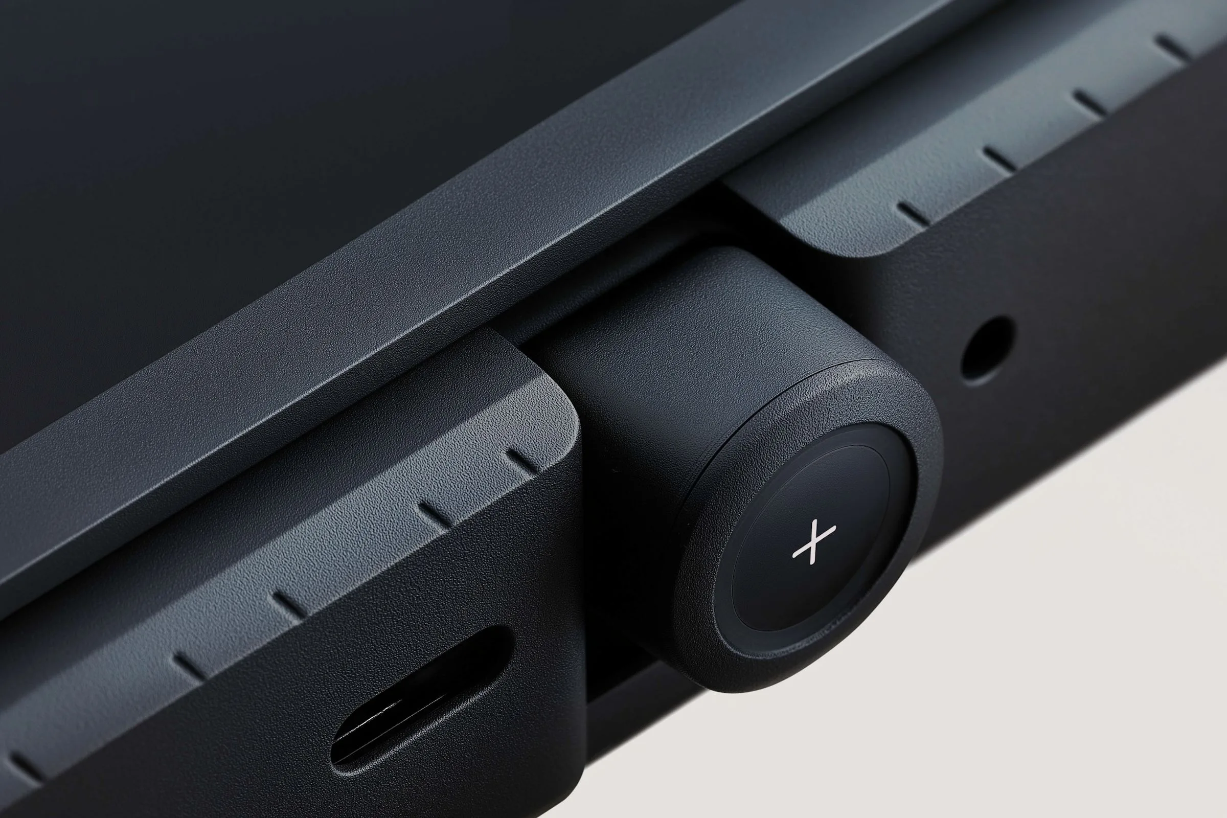 Close-up of a precision-engineered black hardware component with a dial and calibration marks, deep tech product design.