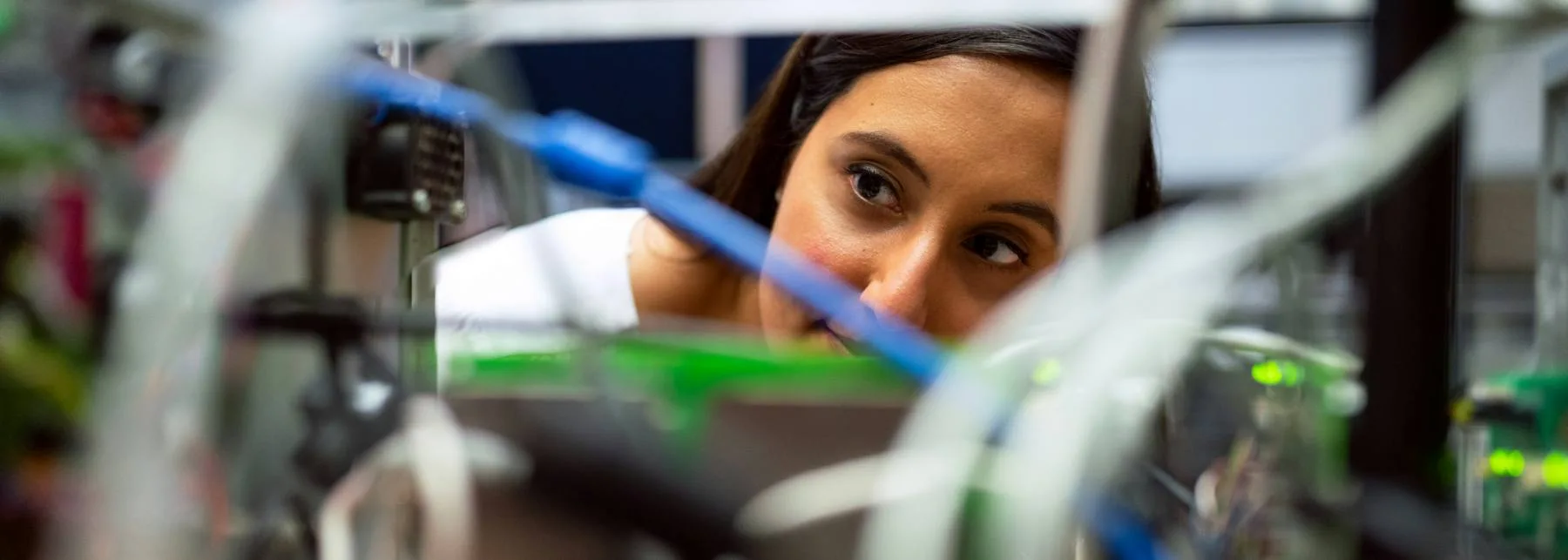 Engineer looking closely through the frame of a prototype in a deep tech research lab.