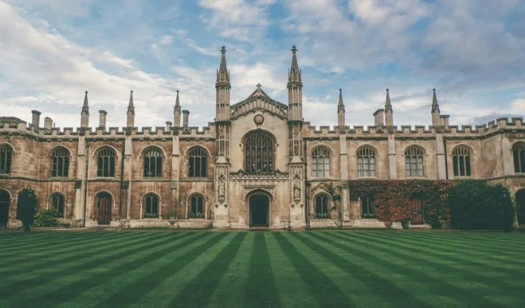 Gothic stone university building behind a striped lawn, representing university research and innovation.