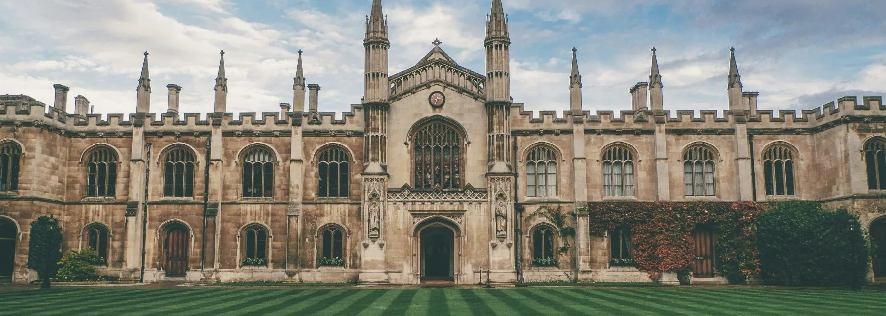 University quadrangle with a gothic stone facade behind a striped lawn, a home for technology transfer and research.